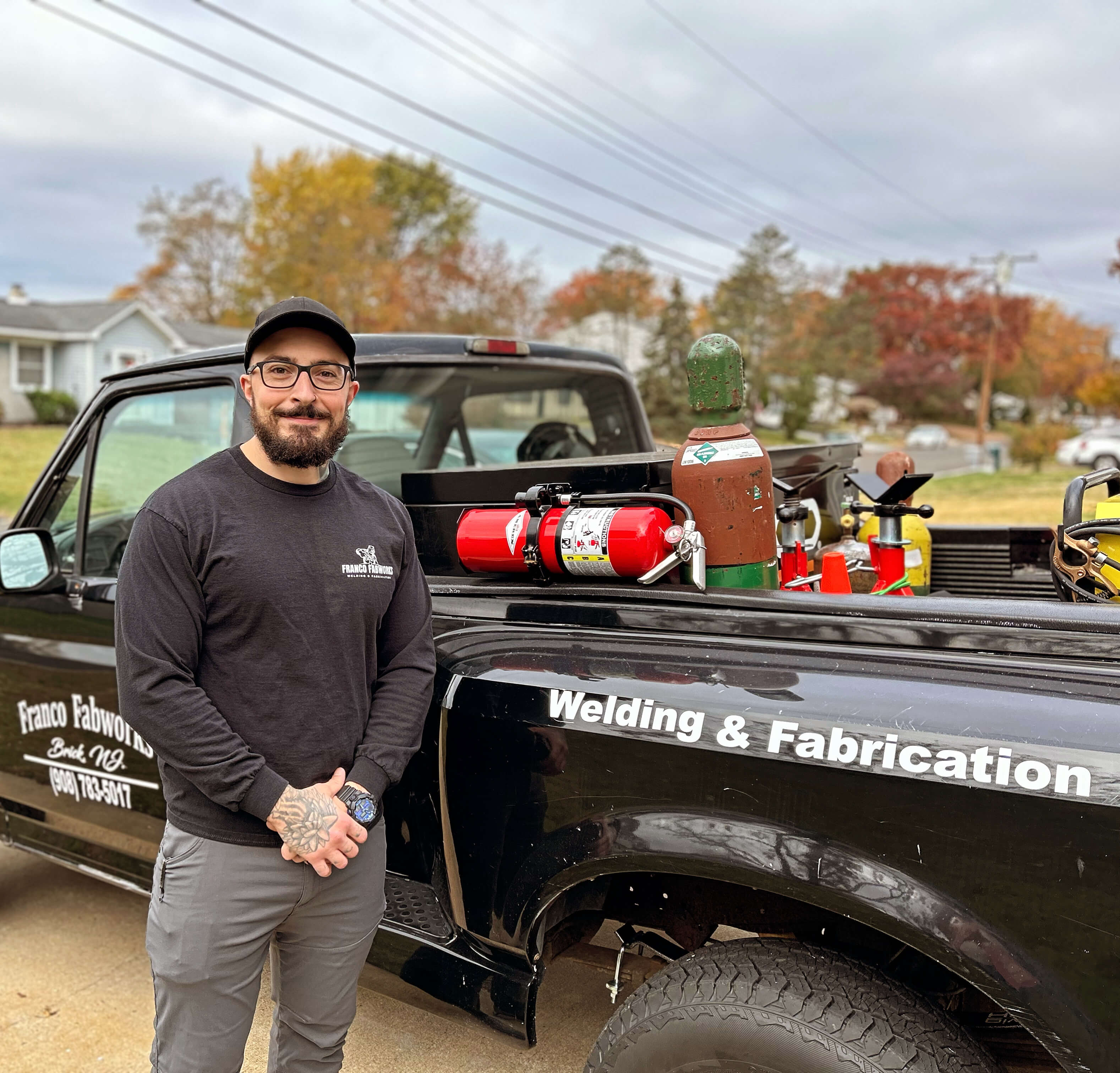 Portrait of Louis Franco, standing beside his work truck, with the company's logo visible on the truck's side